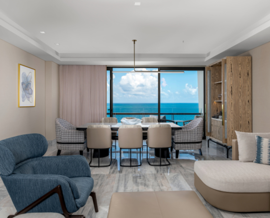 Sala de estar de la suite de lujo frente al mar con sofá y mesa de comedor